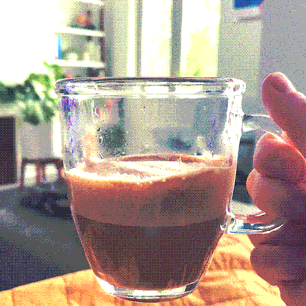 closeup shot of a latte in a clear transparent glass mug with foamy milk